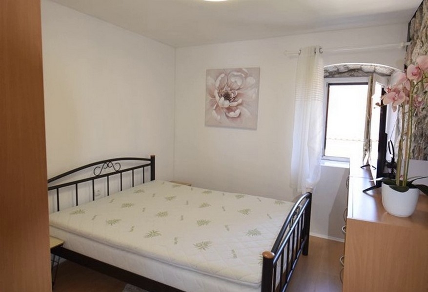 Ložnice s manželskou postelí a kamennou zdí
