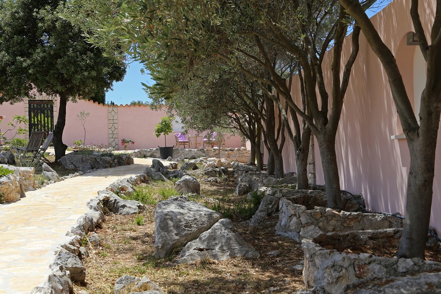 Zahradní cesta se stromy a přírodními kameny vedle domu