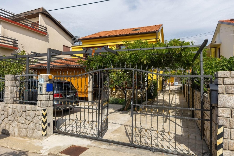 Vstup do nemovitosti s bránou a žlutým domem