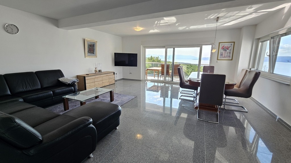 Obývací pokoj s velkou pohovkou a výhledem na terasu