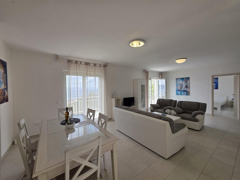 Obývací pokoj s pohovkou a jídelním koutem, výhled na moře