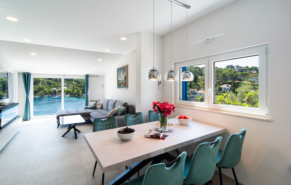 Světlý obývací pokoj s jídelním stolem a výhledem na záliv