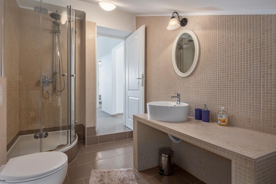 Koupelna s kulatým sprchovým koutem a umyvadlem