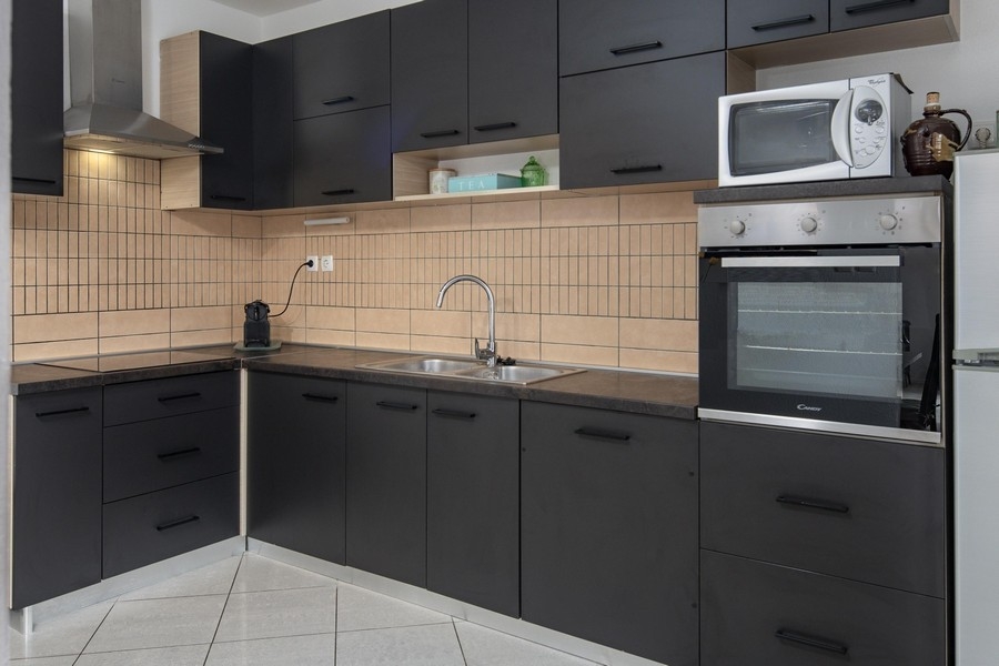 Zařízená kuchyně v tmavém provedení s moderním vybavením