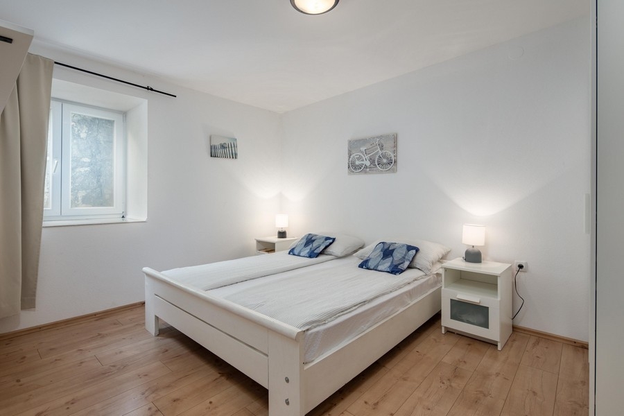 Světlá ložnice s manželskou postelí a dřevěnou podlahou