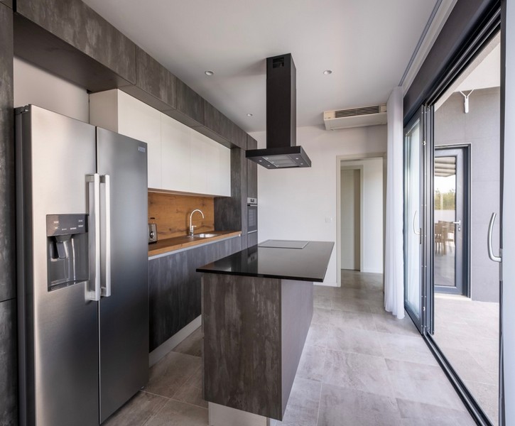 Moderní kuchyně s varným ostrůvkem a vstupem na terasu