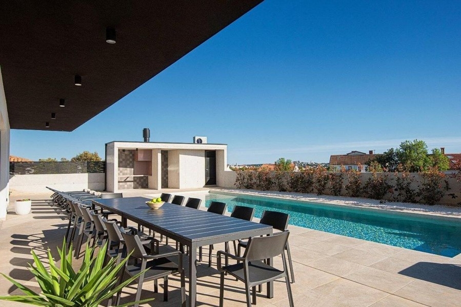 Terasa s velkým jídelním stolem a výhledem na bazén