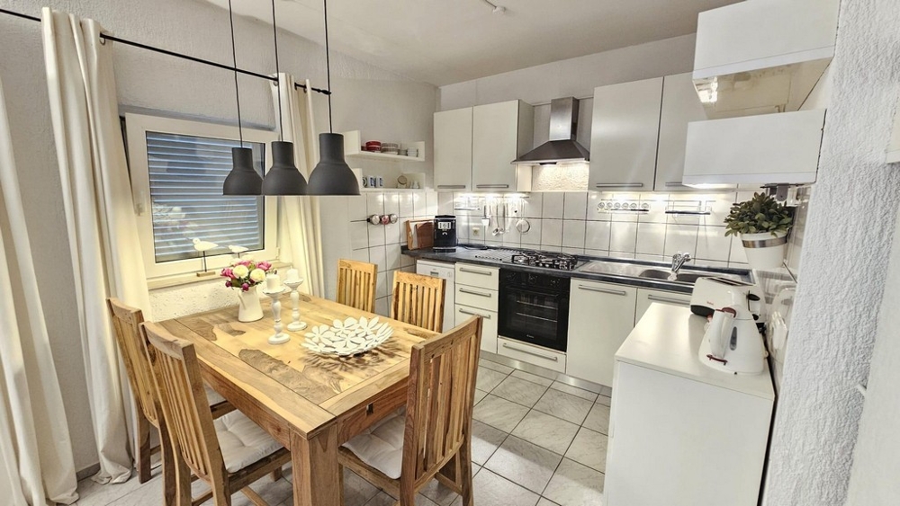 Jídelní kout a kuchyně s dřevěným stolem a moderními lampami