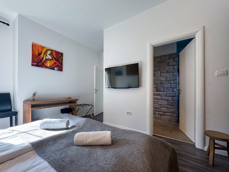 Světlá ložnice s TV a detaily kamenné zdi