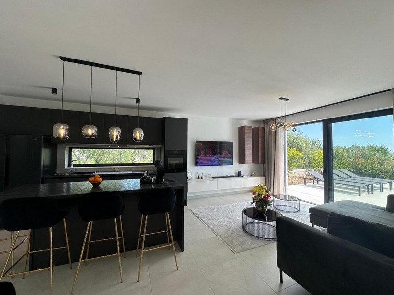 Moderní kuchyně s jídelním koutem a výhledem na terasu.