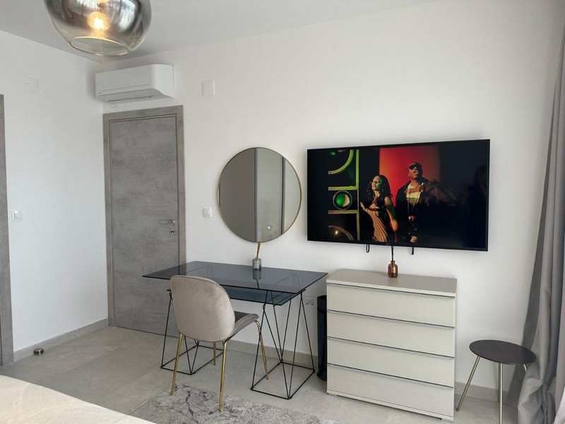 Moderně zařízená ložnice s psacím stolem, zrcadlem a televizí