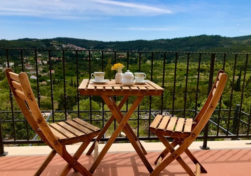 Balkon se stolem a židlemi, výhled na kopce