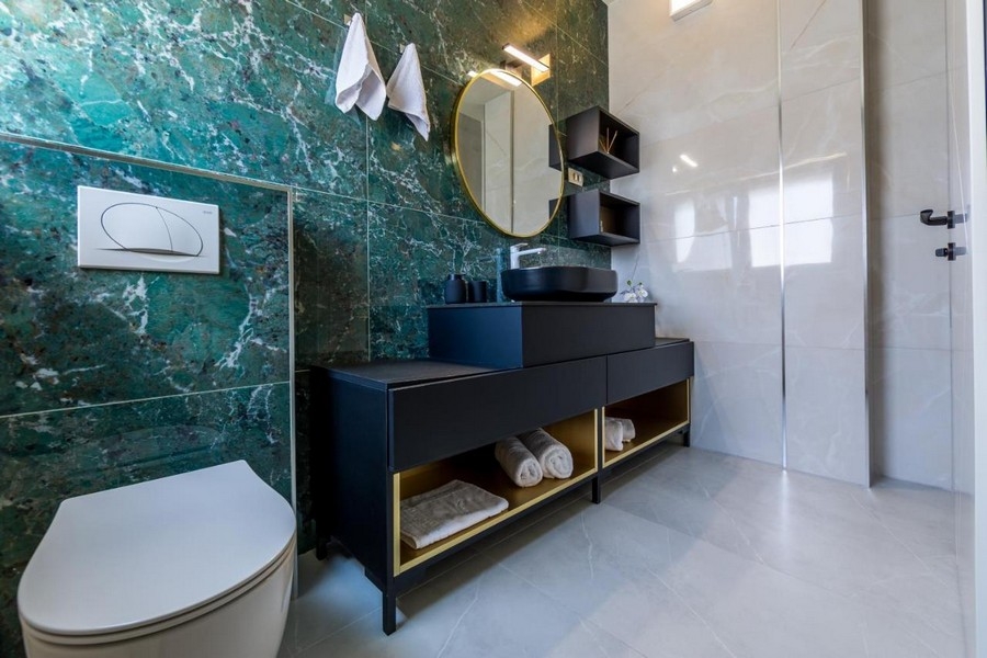 Koupelna se zelenou mramorovou stěnou a moderním umyvadlem