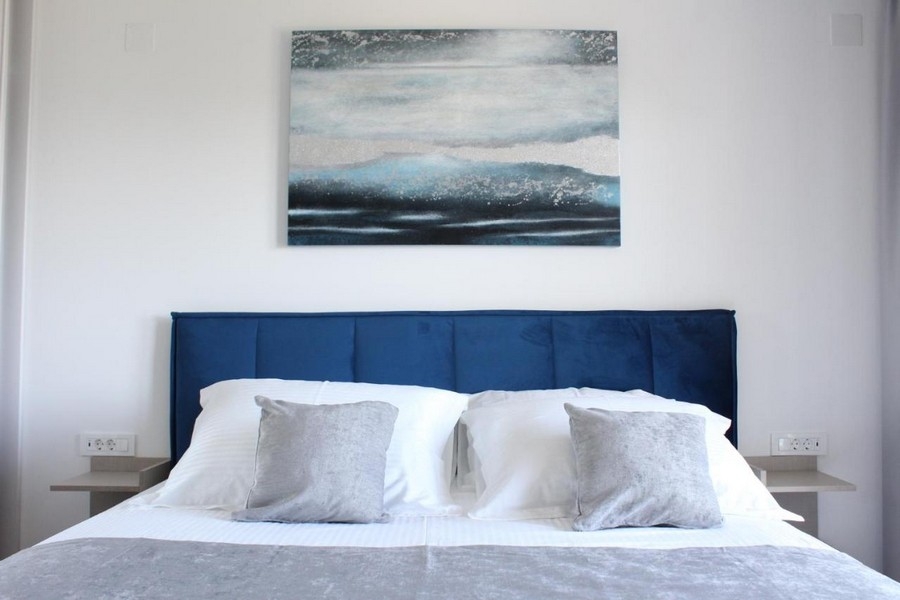 Manželská postel v moderní ložnici s dekorativní nástěnnou malbou
