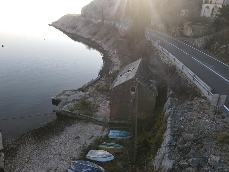 Kamenný dům přímo u moře pod pobřežní silnicí v Chorvatsku