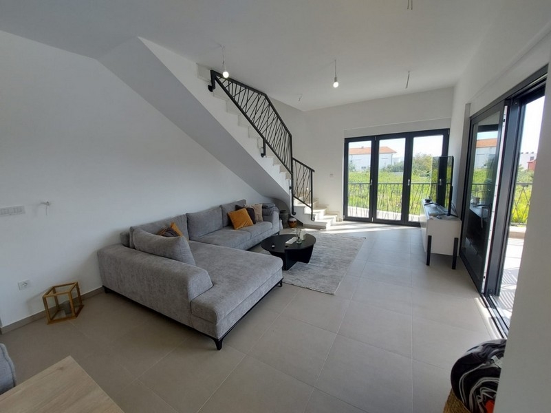 Světlý obývací pokoj s pohovkou a schodištěm