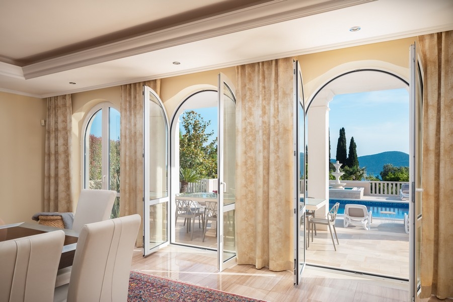 Obývací pokoj s velkými okny a výhledem na bazén