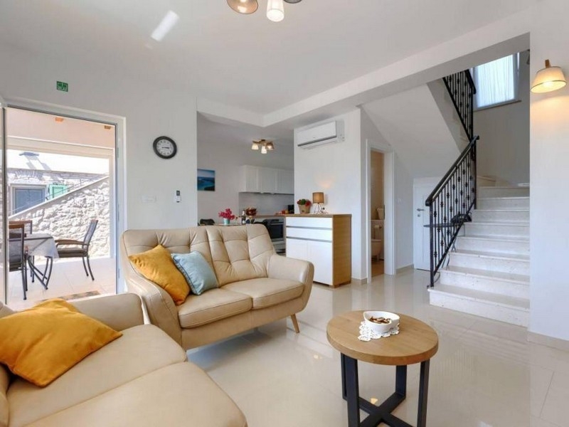 Obývací část se sedací soupravou, schodištěm a vstupem na terasu