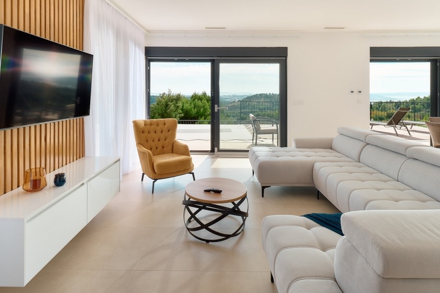 Otevřený obývací prostor s celoplošnými okny a vstupem na terasu