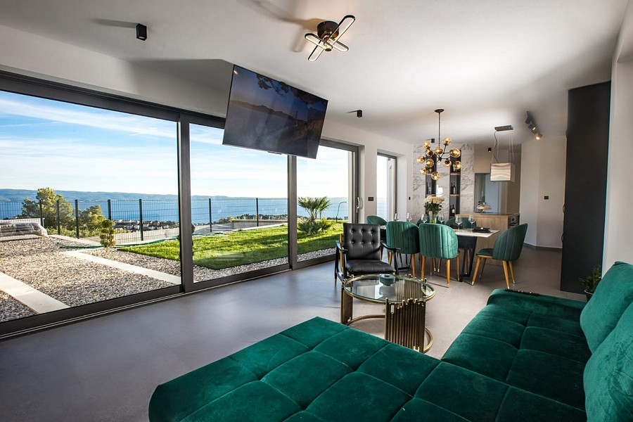 Moderní obývací pokoj s velkými prosklenými čely a výhledem na moře