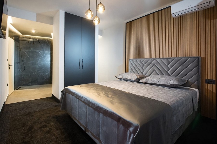 Ložnice s dřevěnou panelovou stěnou a integrovaným sprchovým koutem