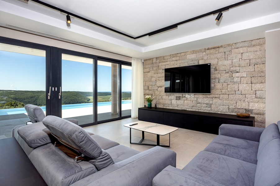 Obývací pokoj s panoramatickými okny a výhledem do zeleně