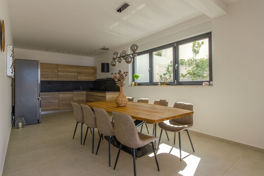 Jídelní kout s velkým dřevěným stolem a moderním osvětlením