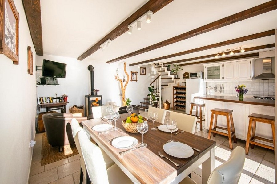 Obývací část s dřevěnými trámy, krbem a kuchyní