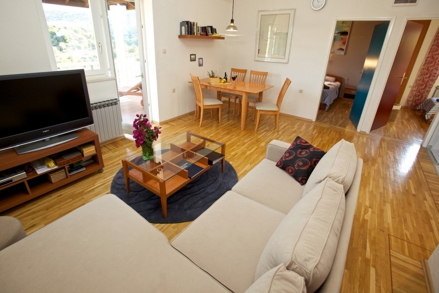 Obývací pokoj s pohovkou, dřevěnou podlahou a jídelním koutem