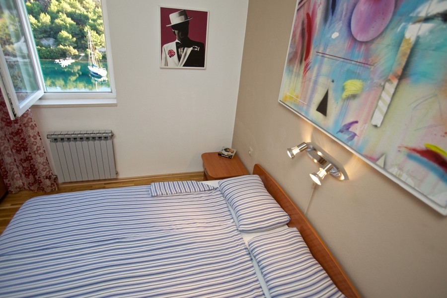 Ložnice s výhledem z okna na záliv a plachetnici