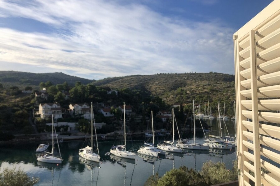 Výhled na moře z balkonu s plachetnicemi v zálivu