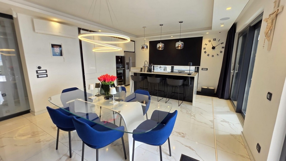 Jídelní kout se skleněným stolem a moderní kuchyní