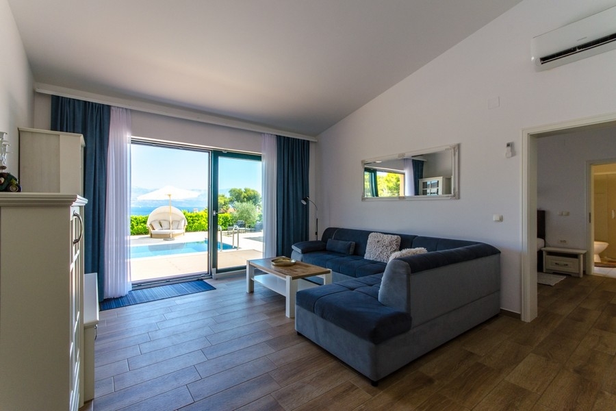 Obývací část s pohovkou a terasovými dveřmi k bazénu