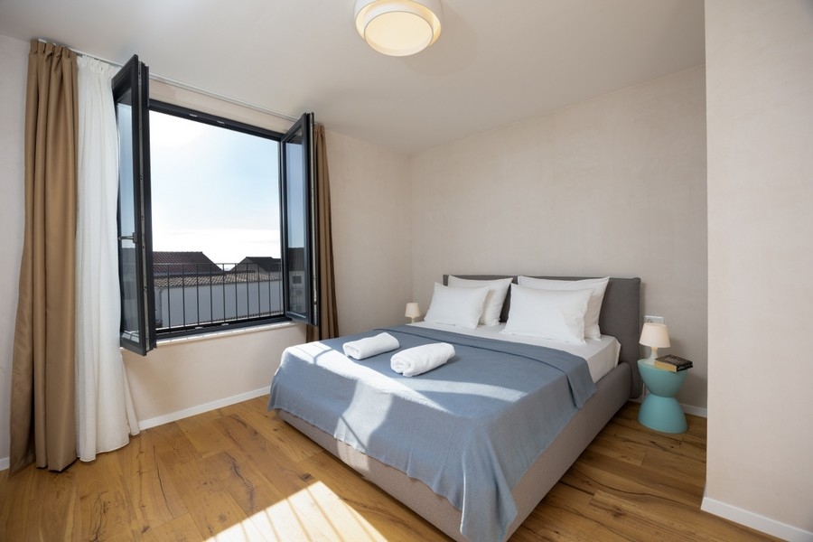 Ložnice s manželskou postelí a otevřeným oknem