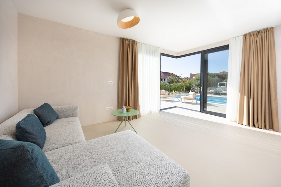 Obývací pokoj s pohovkou a výhledem na terasu a bazén