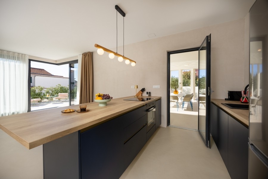 Moderní kuchyně s varným ostrůvkem a vstupem na terasu