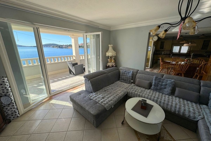 Světlý obývací pokoj s velkými okny a výhledem na moře