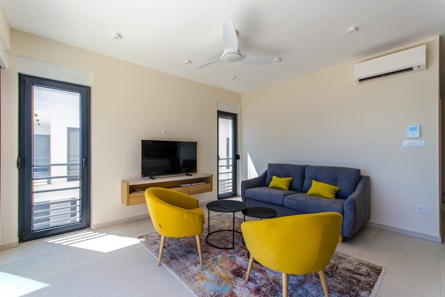 Moderní obývací pokoj s klimatizací a velkými okny s výhledem na moře