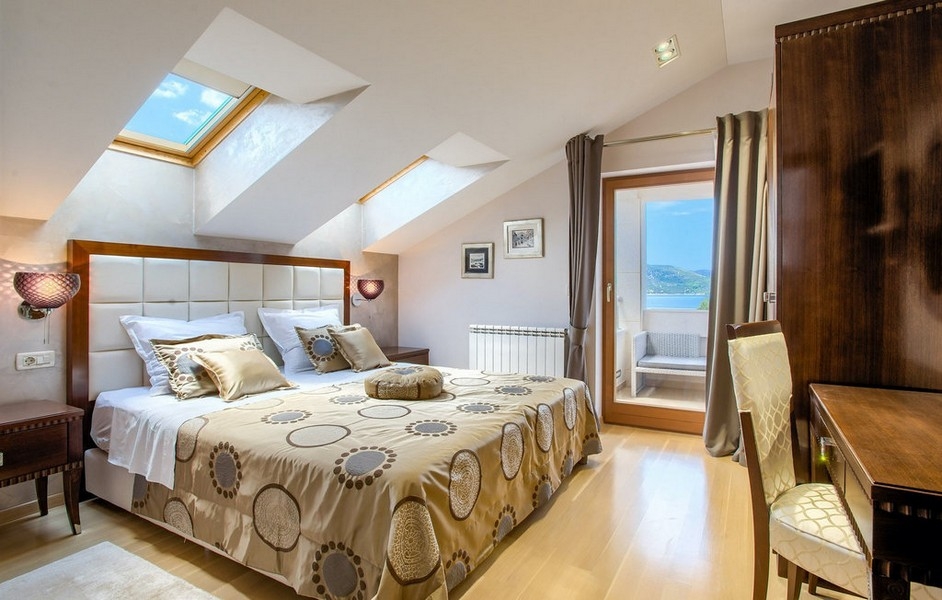 Ložnice se zkosenými stropy a přístupem na balkon s výhledem na moře
