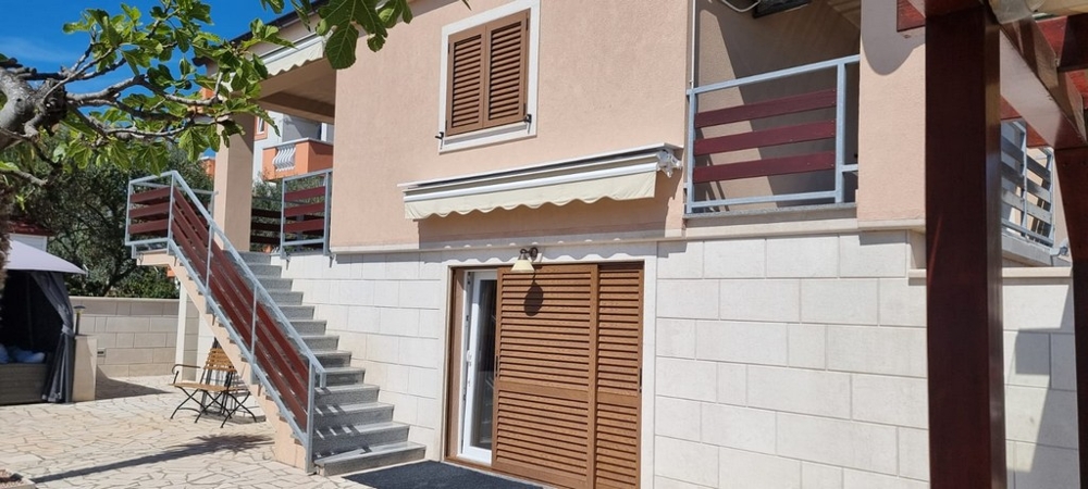 Fasáda domu s balkonem, markýzy a samostatnými vstupy do bytových jednotek