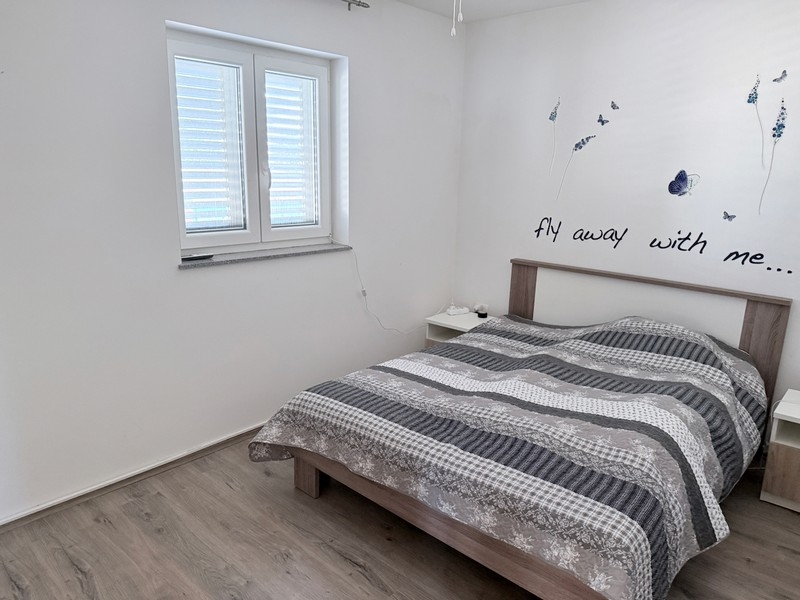 Ložnice s manželskou postelí a oknem v klidné lokalitě na ostrově Pag