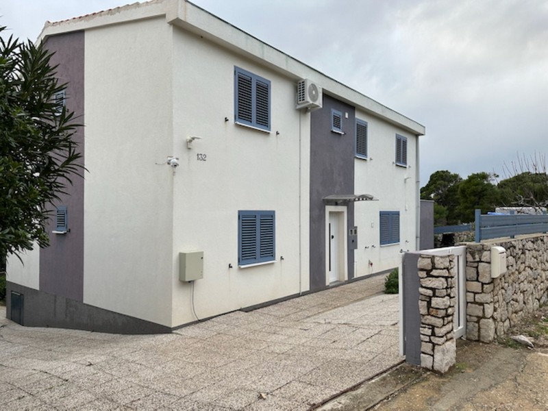 Fasáda domu se vstupním prostorem a parkovacím místem na oploceném pozemku v Chorvatsku