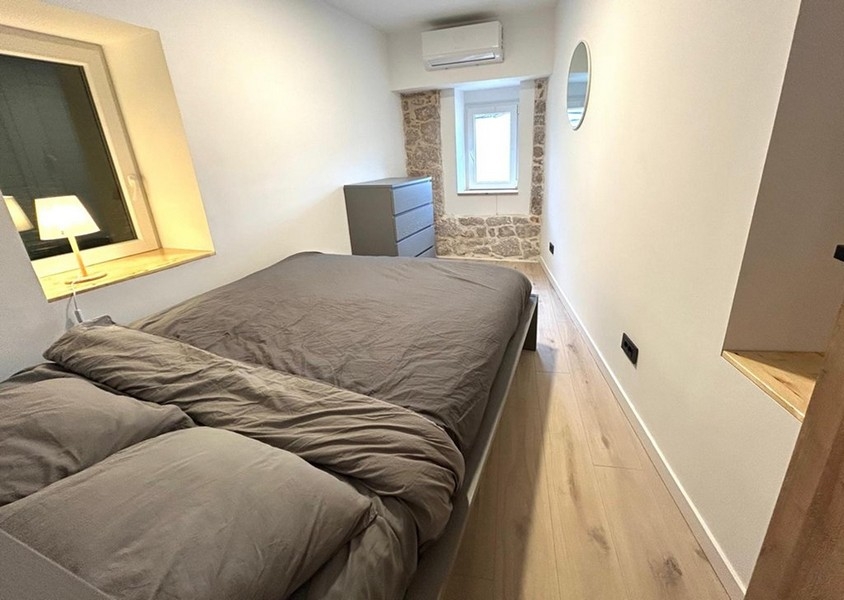 Ložnice s manželskou postelí a viditelnou zdí z přírodního kamene