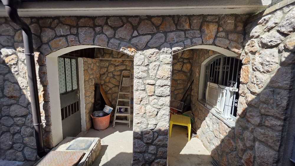 Krytý vstupní prostor s fasádou z přírodního kamene a oblouky