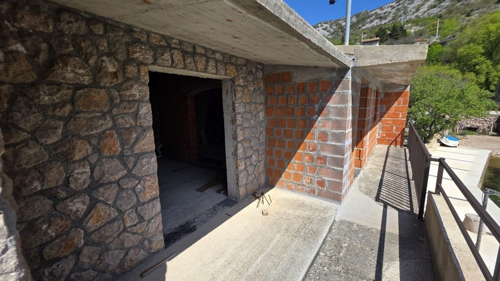 Venkovní prostor s přírodní kamennou zdí a krytou terasou