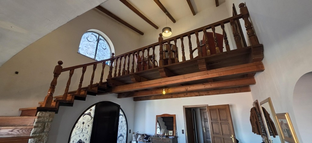 Obývací pokoj s krbem, odhalenými dřevěnými trámy a galerií