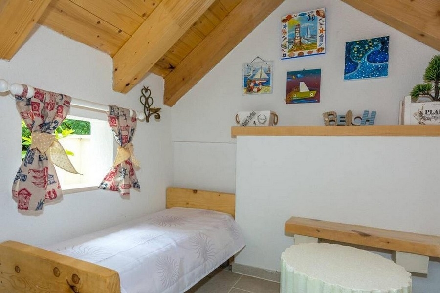 Spací kout v podkroví s dřevěnými trámy a útulnou atmosférou