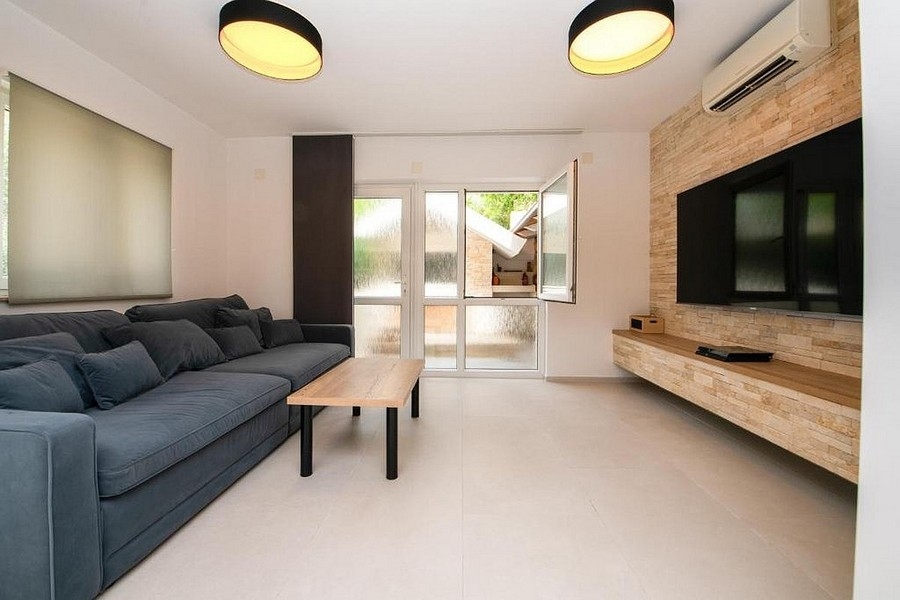 Moderní obývací pokoj se sedací soupravou, TV stěnou a vstupem na terasu