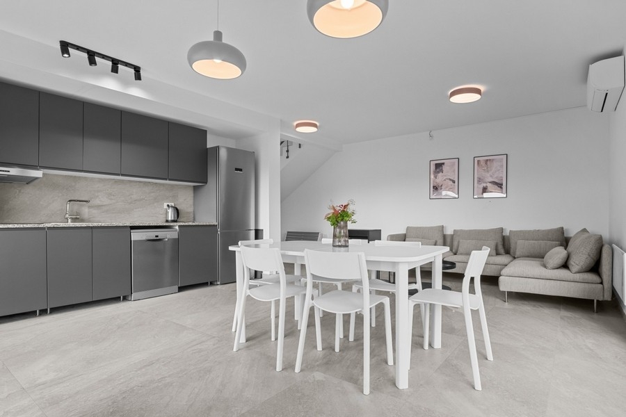 Světlý obývací pokoj s pohovkou a integrovanou kuchyní v otevřeném půdorysu