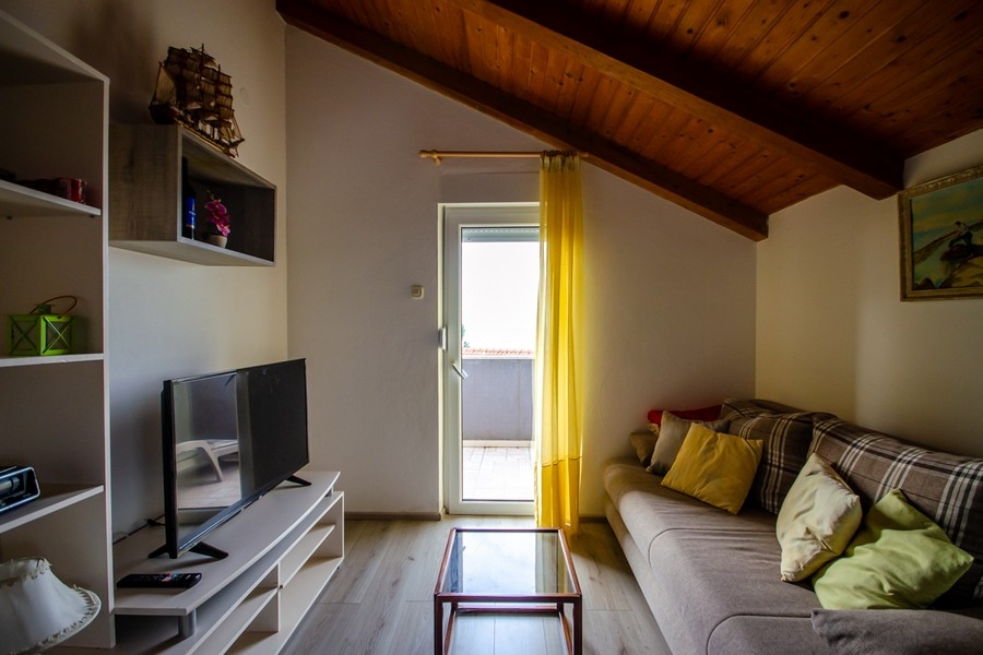 Obývací pokoj v podkroví se sedací soupravou a vstupem na balkon